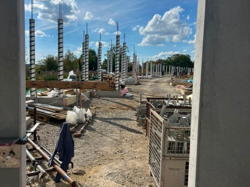 Plac budowy z rzędami prefabrykowanych słupów żelbetowych — widok z wnętrza konstrukcji